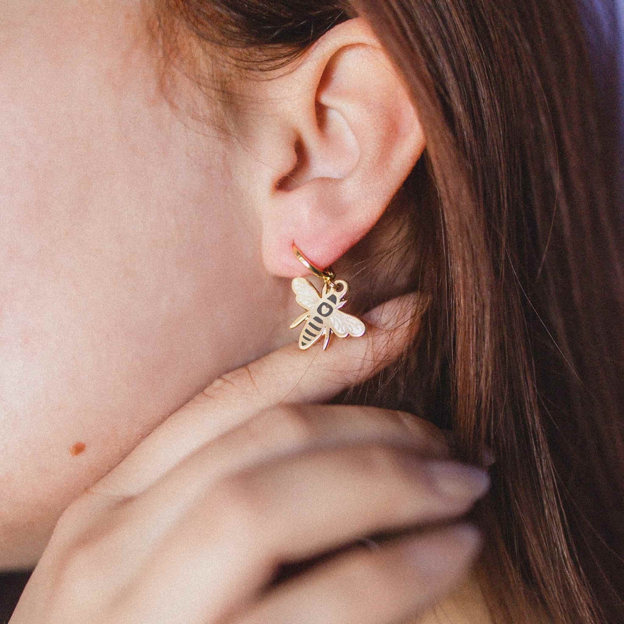 Close-up of a person wearing a gold bee-shaped earring.