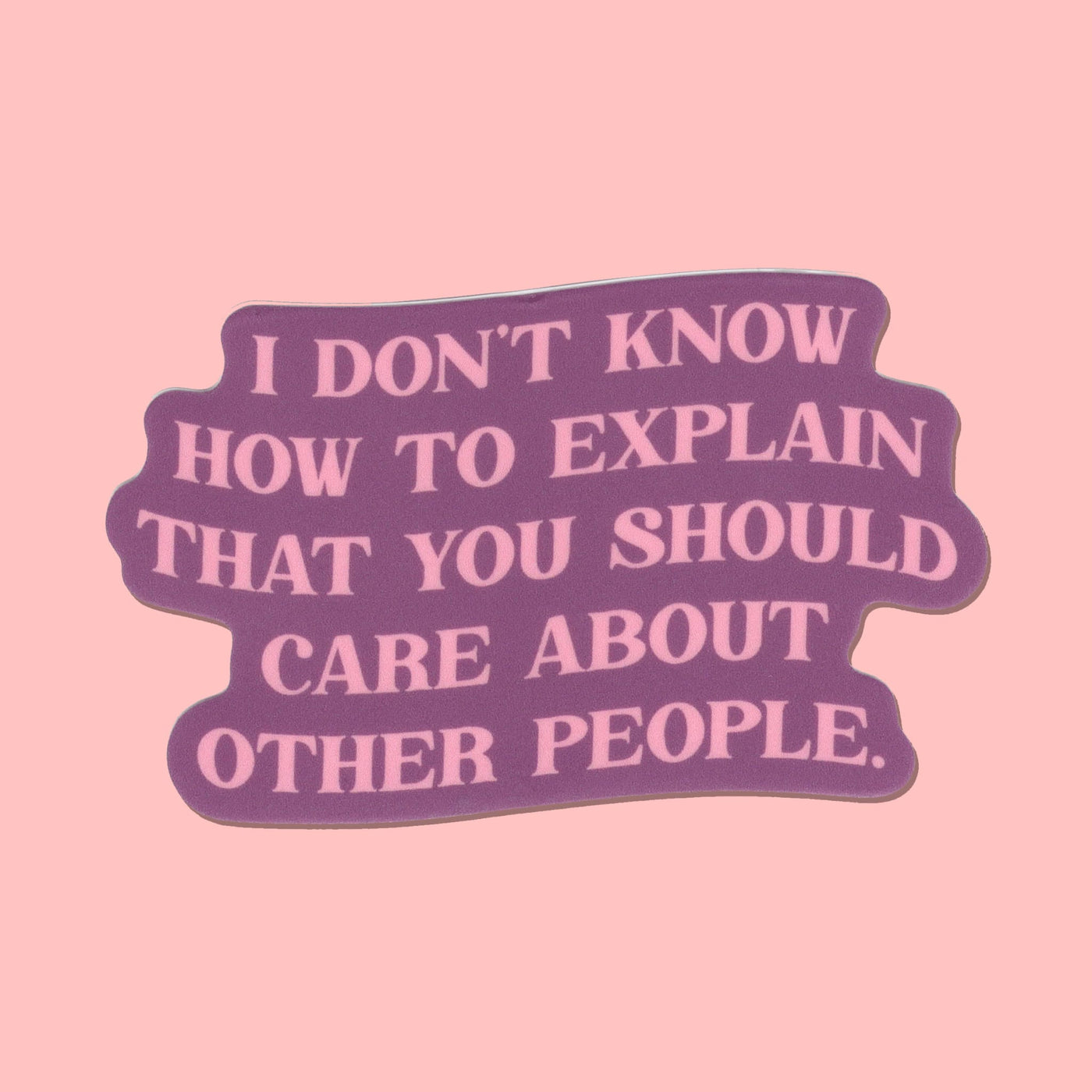 A die-cut sticker with a wavy, organic shape featuring the text 'I DON'T KNOW HOW TO EXPLAIN THAT YOU SHOULD CARE ABOUT OTHER PEOPLE.' in light pink lettering on a dark purple background, set against a solid light pink backdrop.